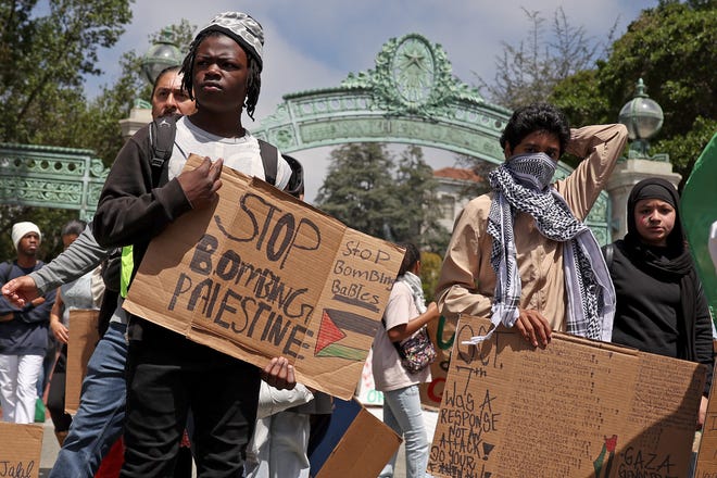Pro-Palestinian protesters carry signs as they march in front of Sather Gate on the UC Berkeley campus on April 22, 2024 in Berkeley, Calif. Hundreds of pro-Palestinian protesters staged a demonstration in front of Sproul Hall on the UC Berkeley campus where they set up a tent encampment in solidarity with protesters at Columbia University who are demanding a permanent cease-fire in the war between Israel and Gaza.