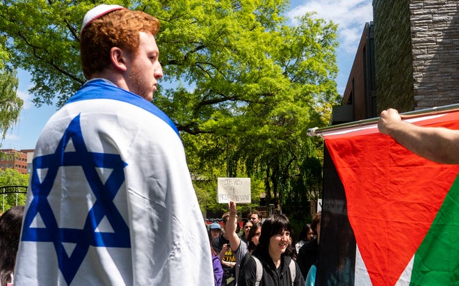 A pro-Israel counter-protester named "Danny", left, stands with an Israeli flag as a pro-Palestinian Jewish protester holds a sign reading "Jews 4 Free Palestine" among the rally and march on April 25, 2024 led by Students for the Justice in Palestine and Philly Palestine Coalition at Temple University in Philadelphia to demand the university divest from companies with ties to the Israeli government.