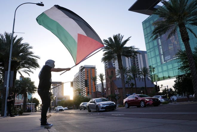 A demonstrator waves a Palestinian flag as cars drive by along University Avenue while ASU students and supporters gather at the universityÕs campus to show their support for Palestinians amid the Israel-Hamas war on Apr 26, 2024.