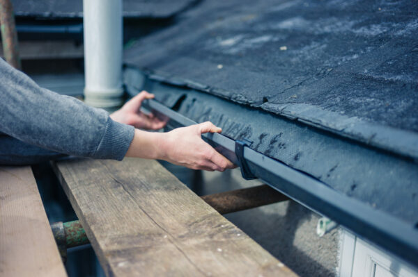 Two hands fixing a roof gutter